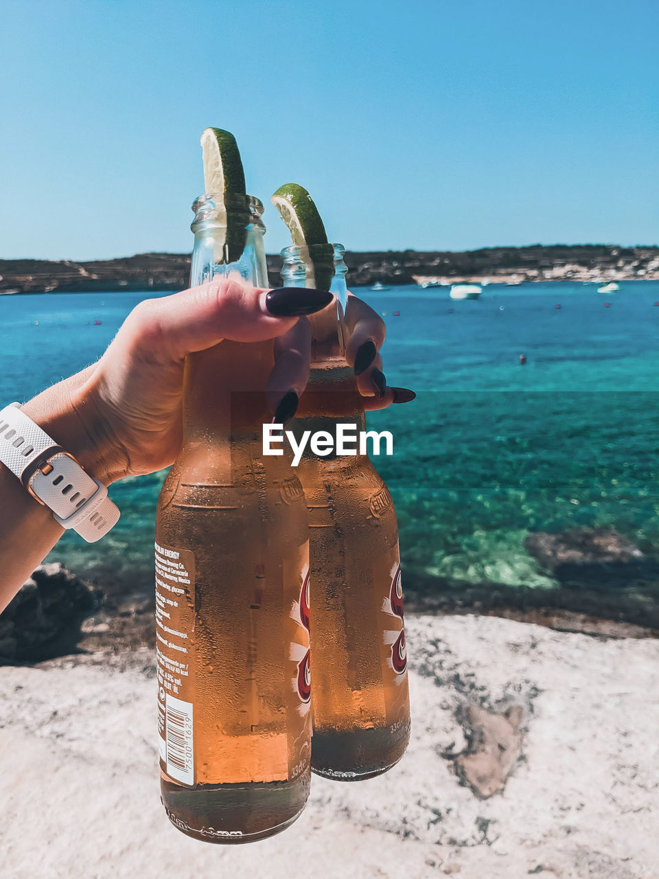 Cropped hand holding beers with lime