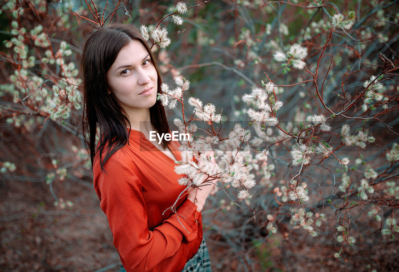 PORTRAIT OF YOUNG WOMAN WITH RED FLOWER