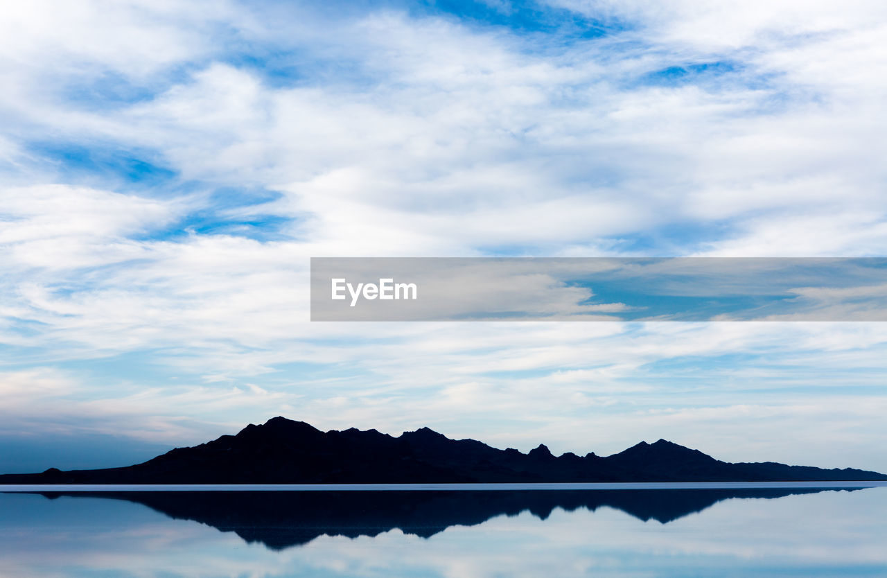 SILHOUETTE MOUNTAIN BY LAKE AGAINST SKY