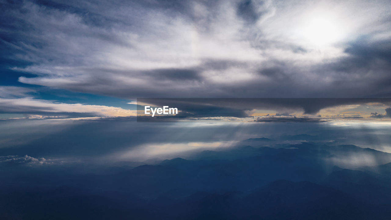 Low angle view of sunlight streaming through clouds