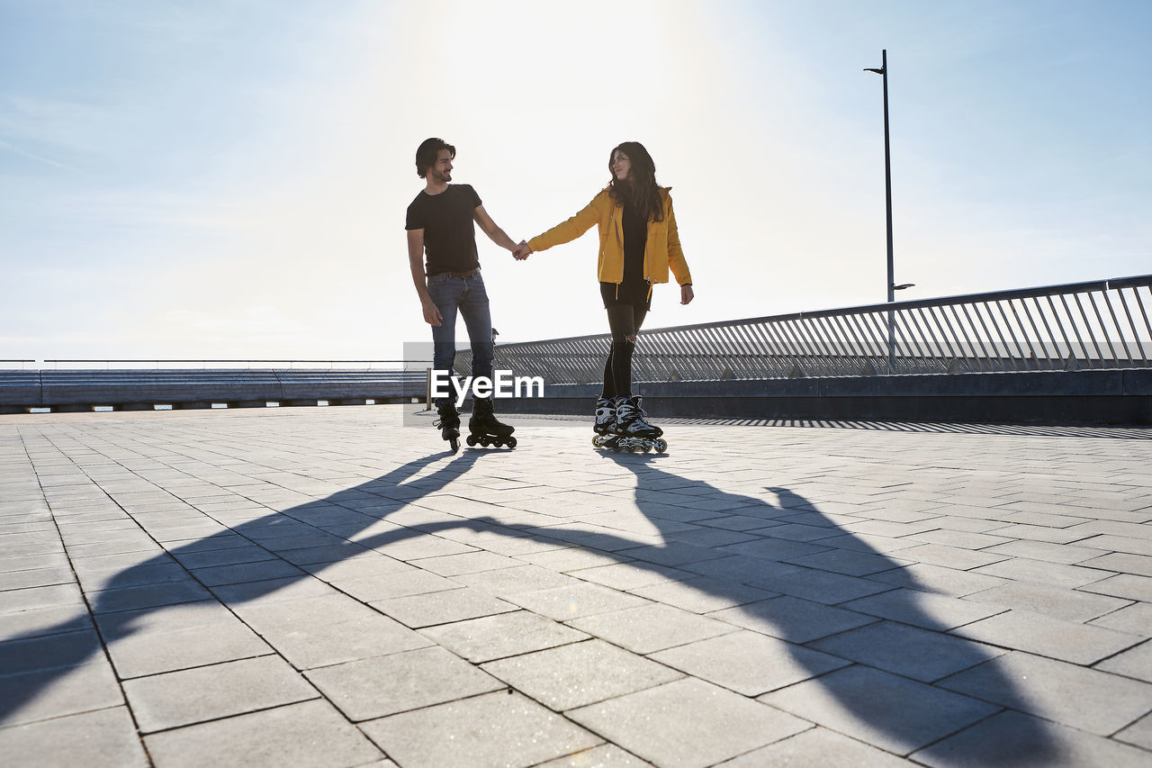 Young couple looking at each other while roller skating on pier during sunny day