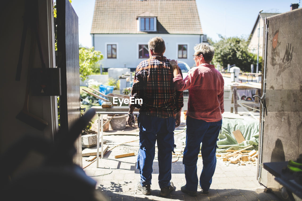 Rear view of senior couple looking at yard while standing in workshop
