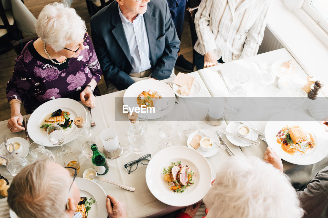 High angle view of senior friends with food in restaurant