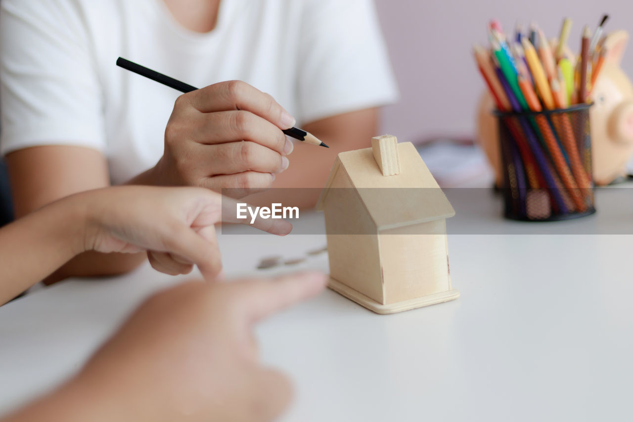 Close-up of woman hand holding pencils on table