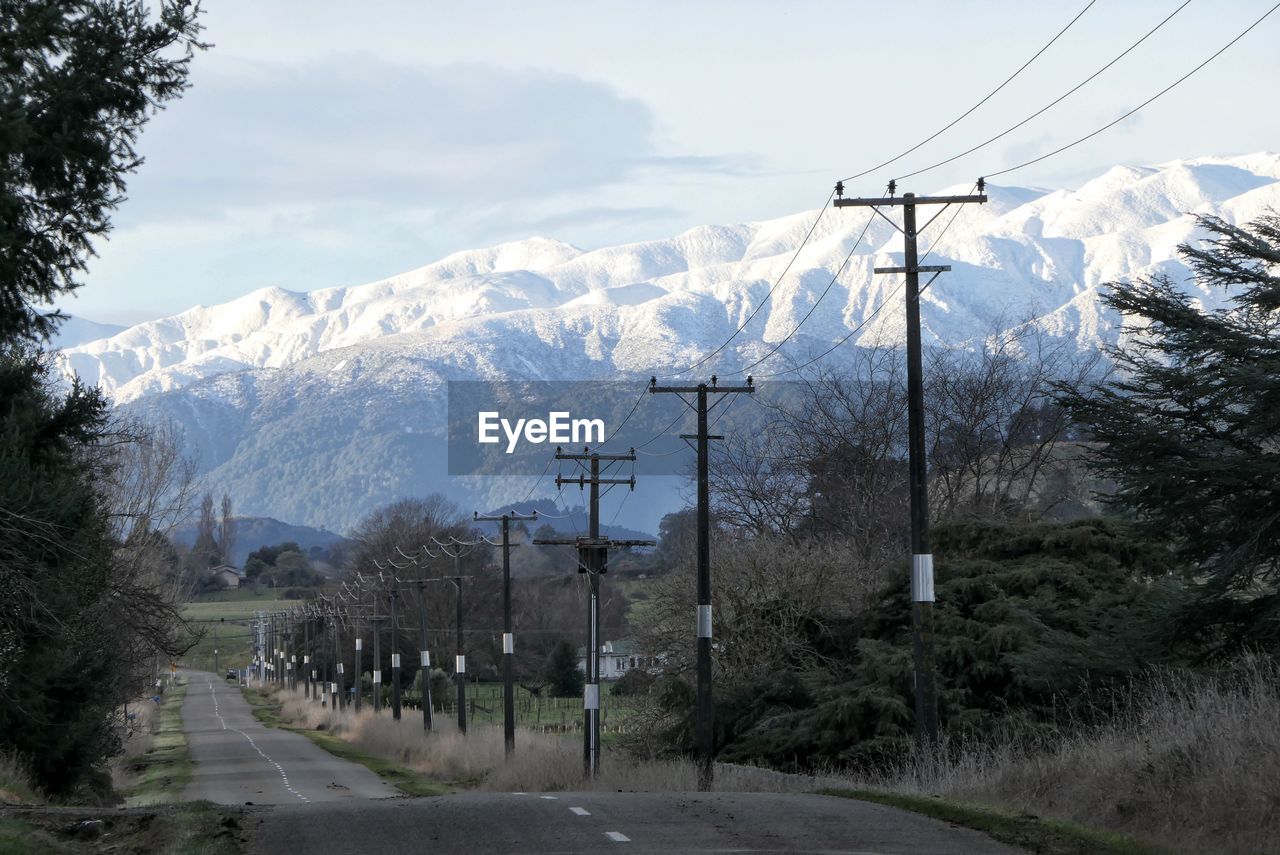 ROAD BY SNOWCAPPED MOUNTAINS AGAINST SKY