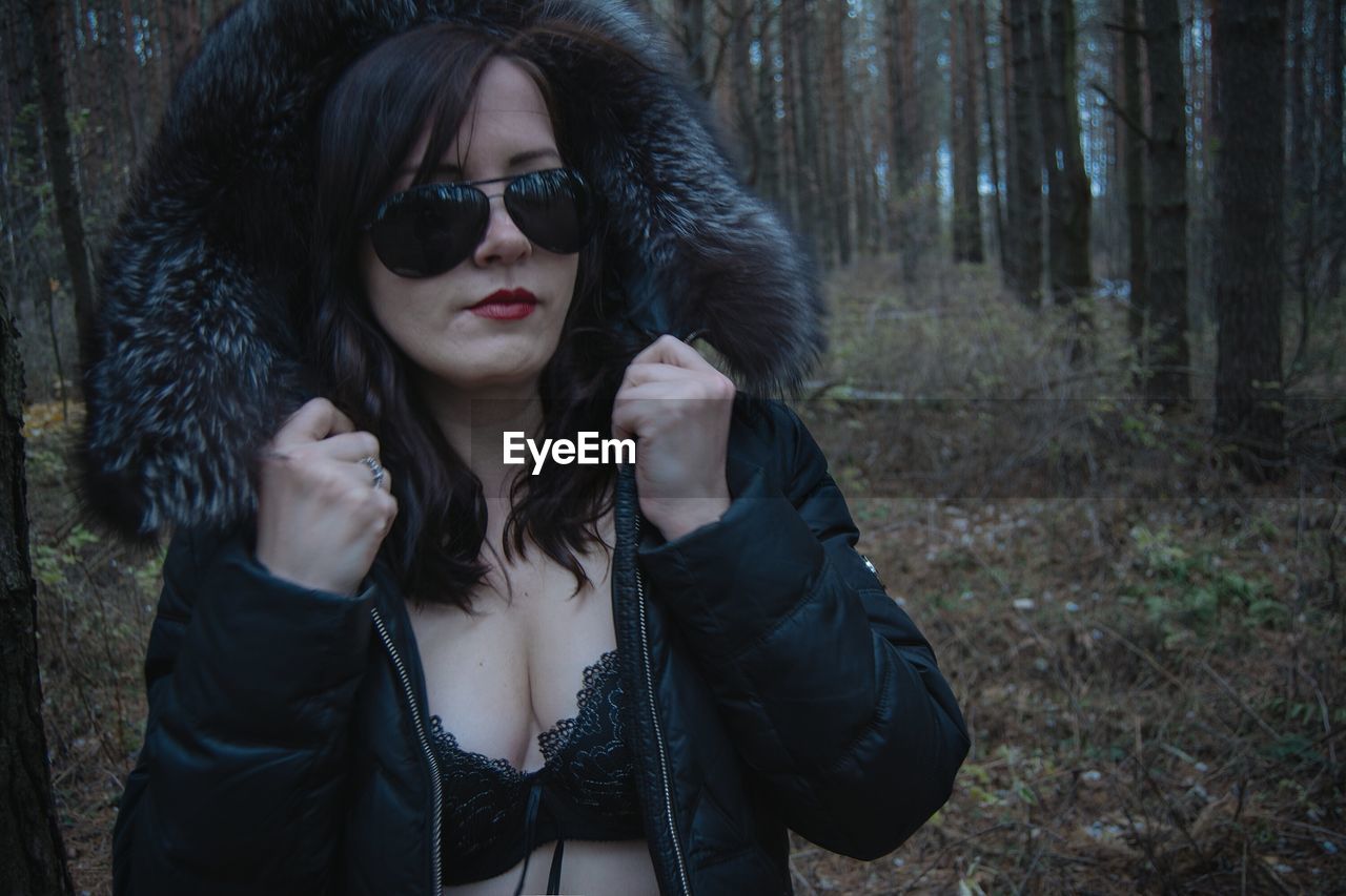 Beautiful woman wearing jacket and sunglasses at forest