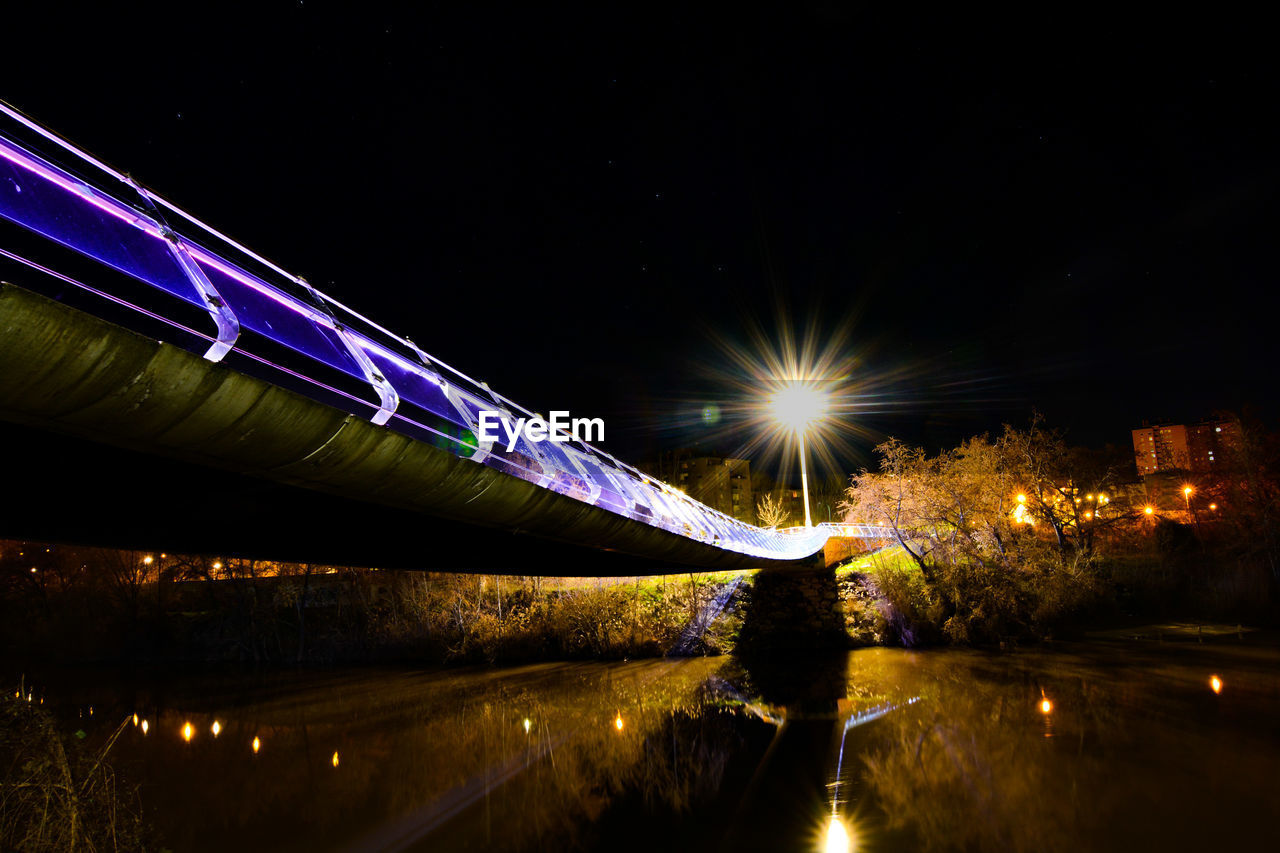 ILLUMINATED LIGHT TRAILS AGAINST SKY AT NIGHT