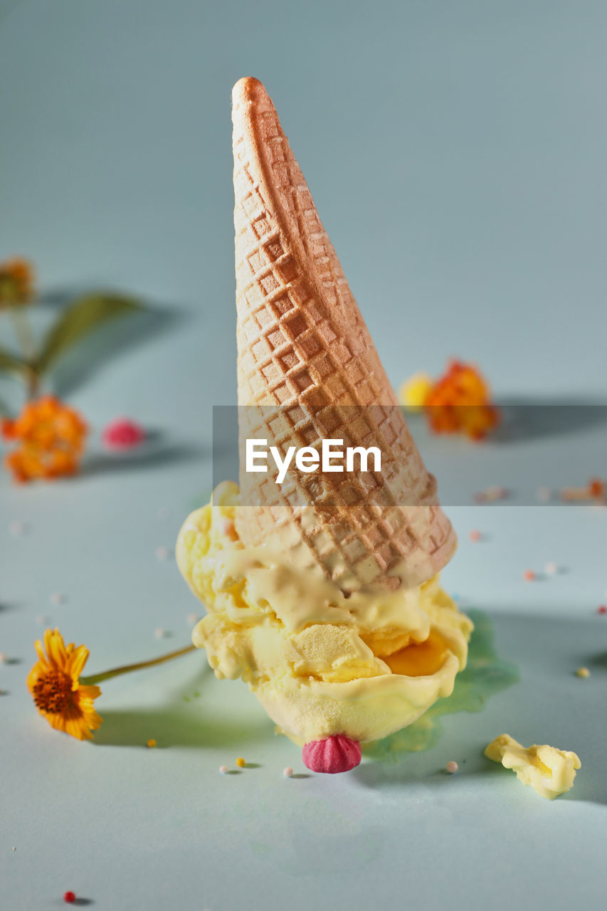 CLOSE-UP OF ICE CREAM CONE AGAINST YELLOW BACKGROUND
