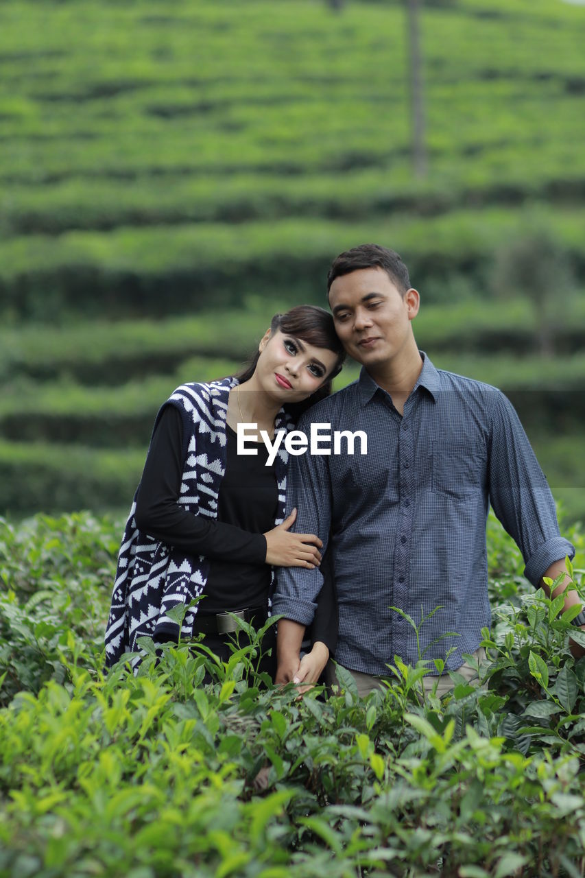 Portrait of smiling couple standing on agricultural field