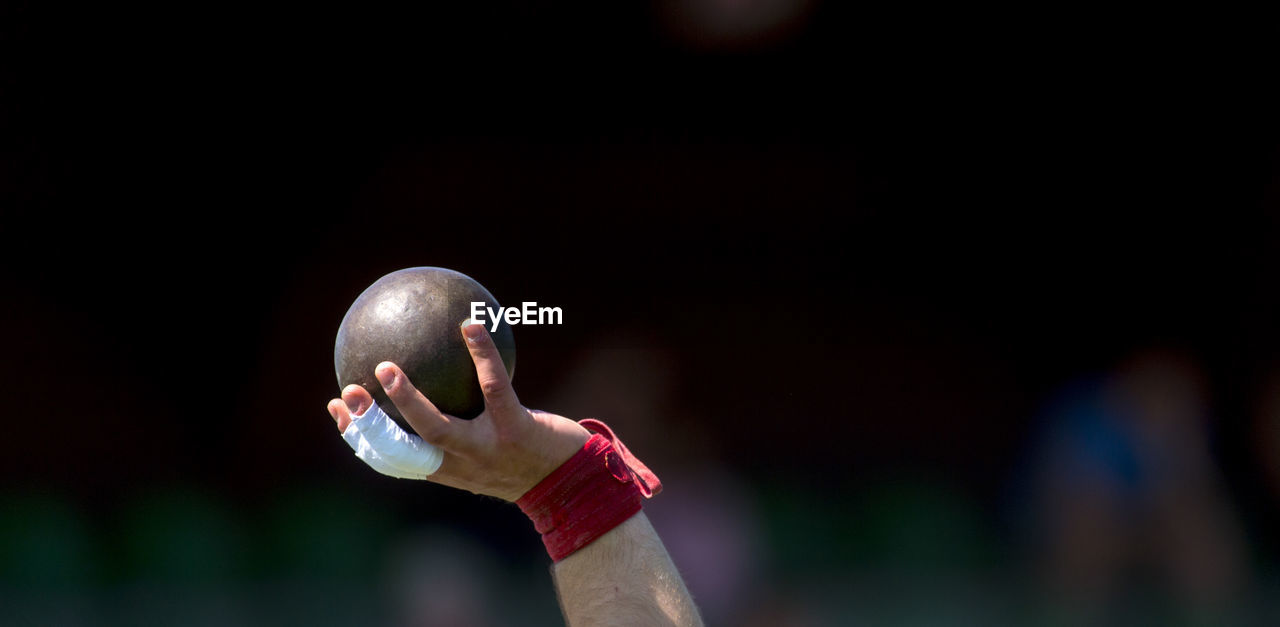 Cropped hand of athlete holding shot put