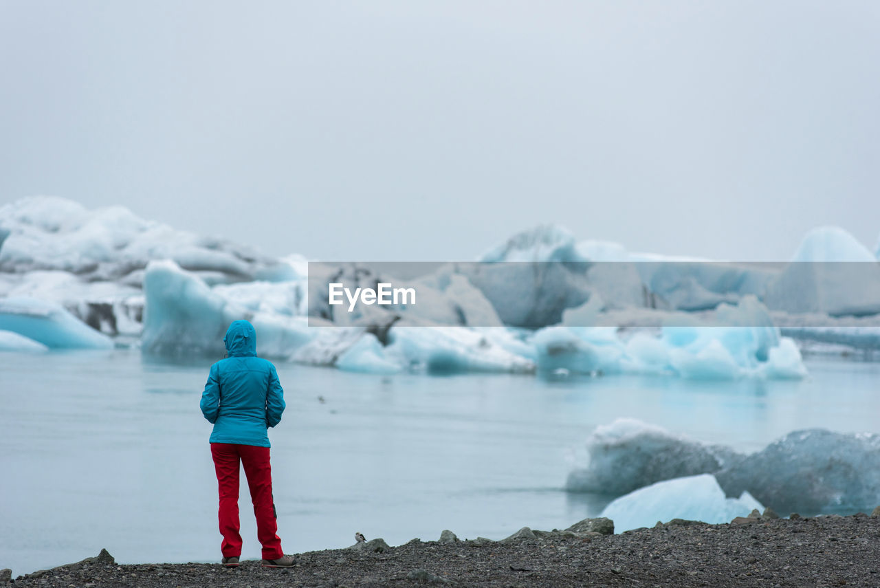 Rear view of woman standing by lake