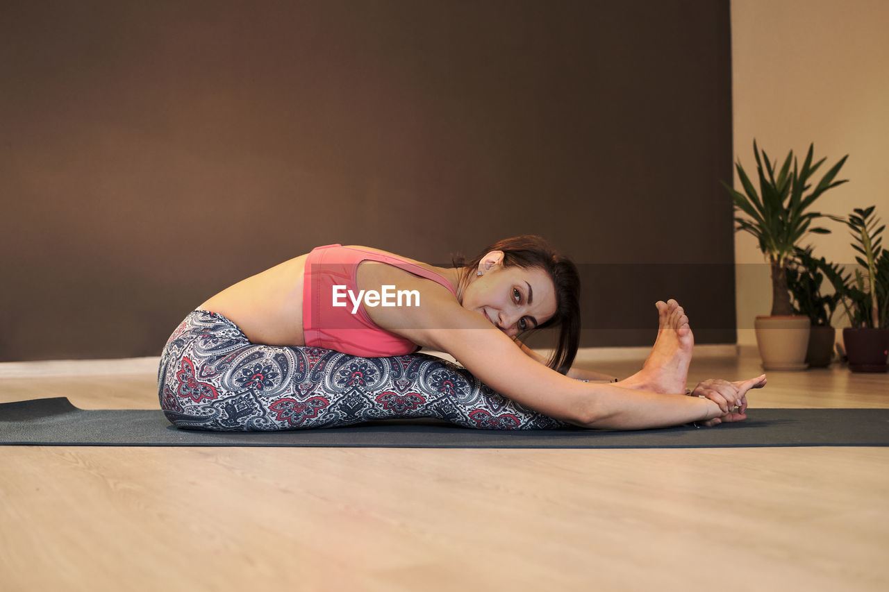 Young woman doing yoga on yoga mat in atmospheric yoga studio