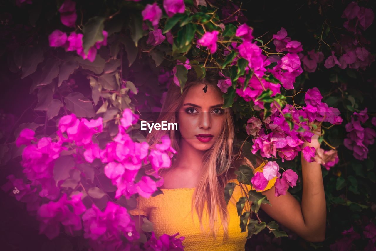 Portrait of beautiful young woman with pink flowers in park