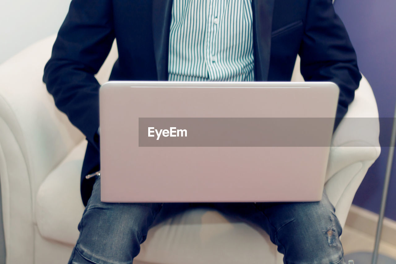 Unrecognizable businessman using laptop while working at home.