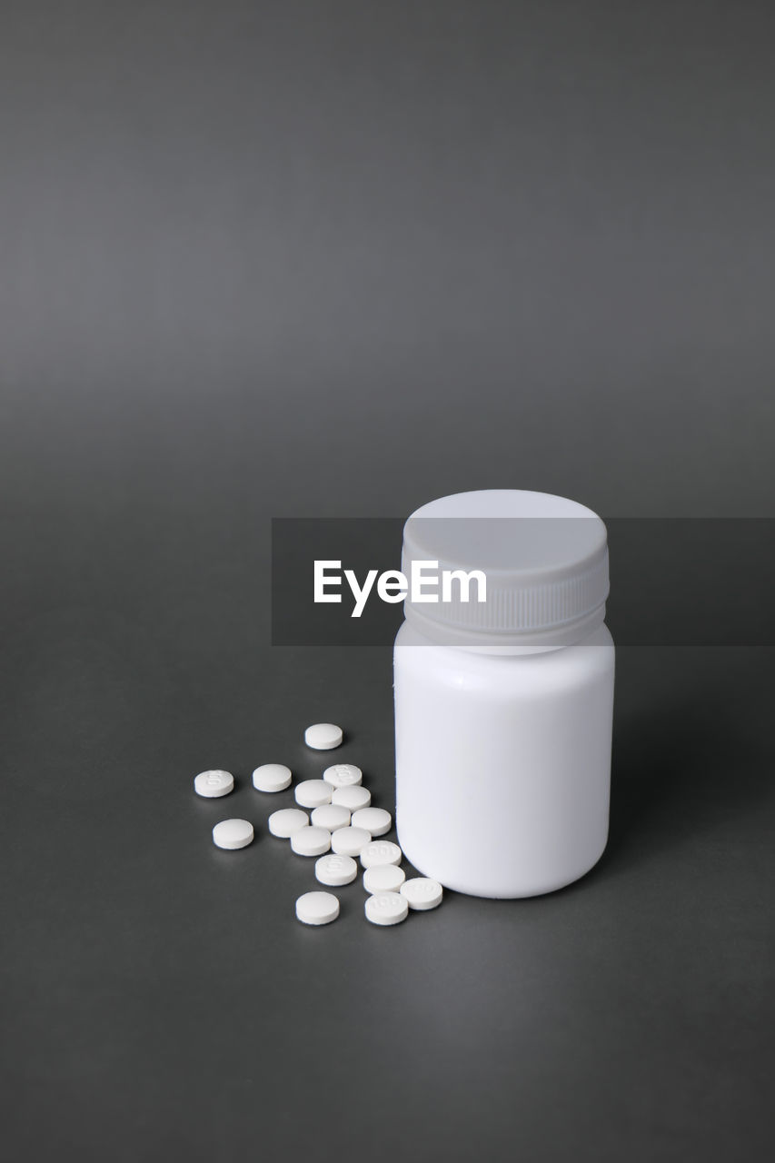 Unlabelled white plastic pill bottle. poured out several small white pills.