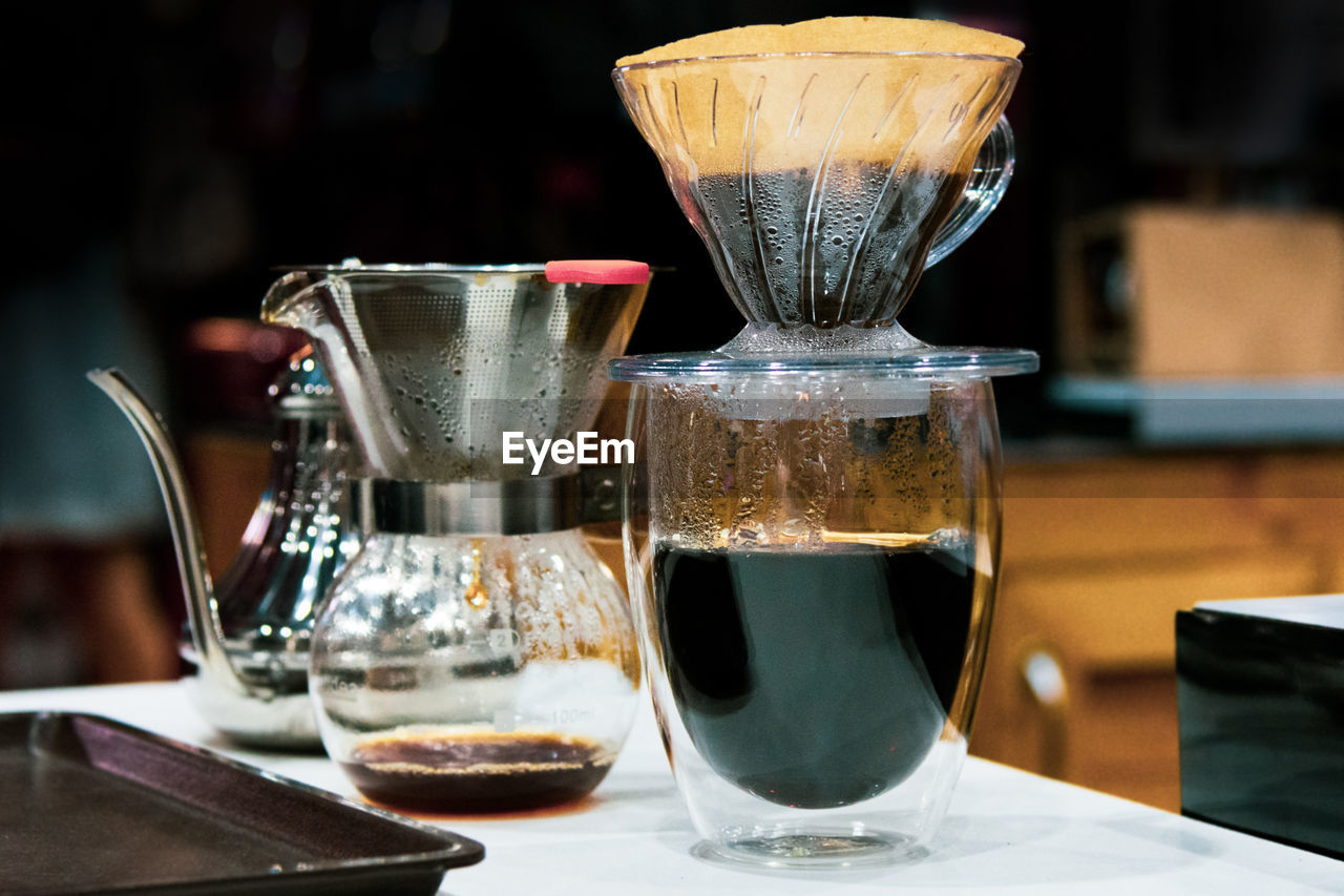 CLOSE-UP OF COFFEE IN GLASS ON TABLE