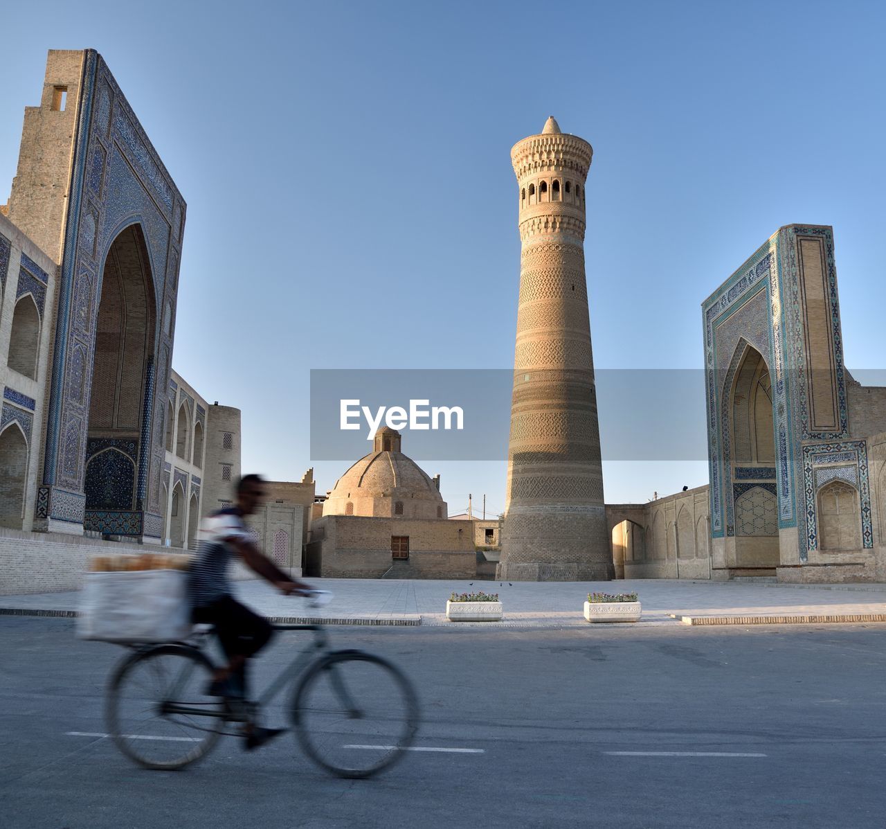 Blurred motion of man riding bicycle on street building in city