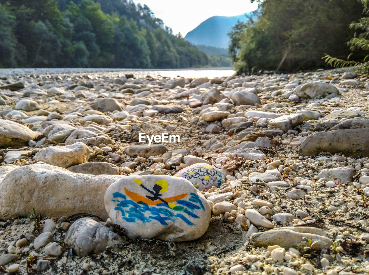 nature, rock, land, shore, water, sea, no people, beach, beauty in nature, day, tranquility, scenics - nature, tree, stone, plant, mountain, pebble, environment, coast, outdoors, tranquil scene, body of water, sky, landscape, wilderness, travel, non-urban scene