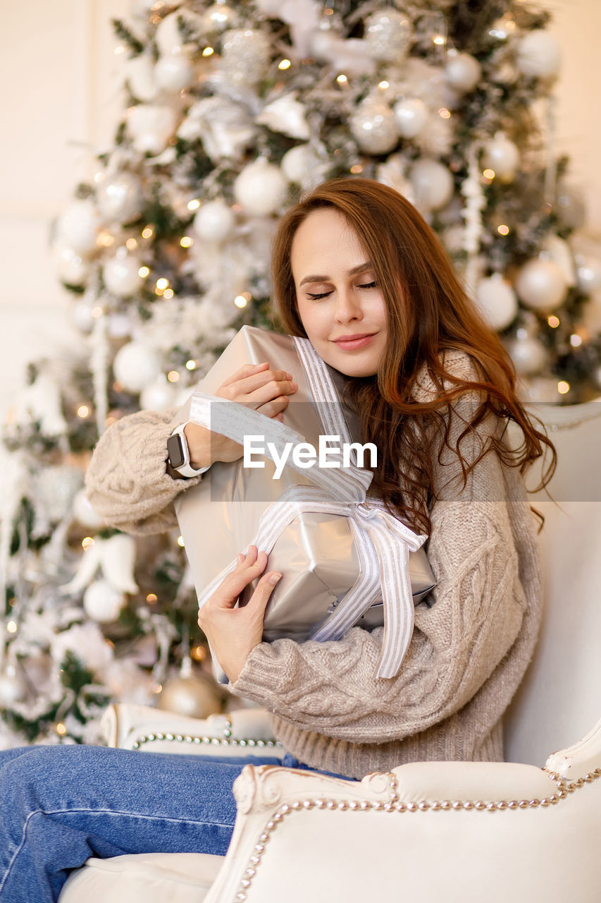 Young woman in a sweater and jeans on the background of christmas decorations