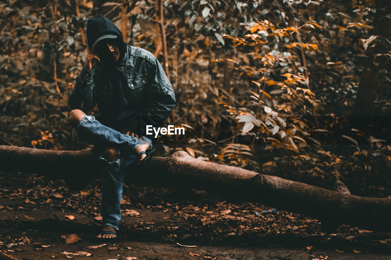 Man sitting on log in forest