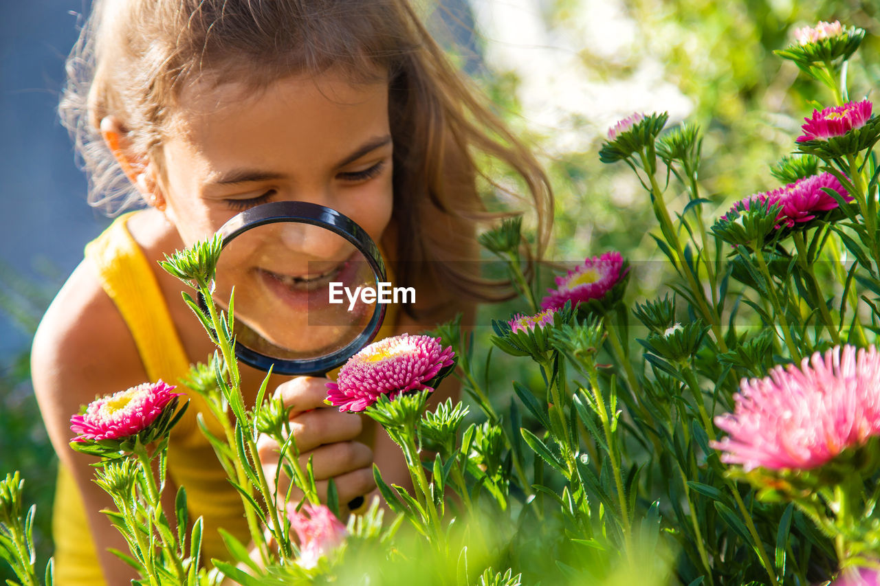 Cute girl looking at flower through magnifying glass