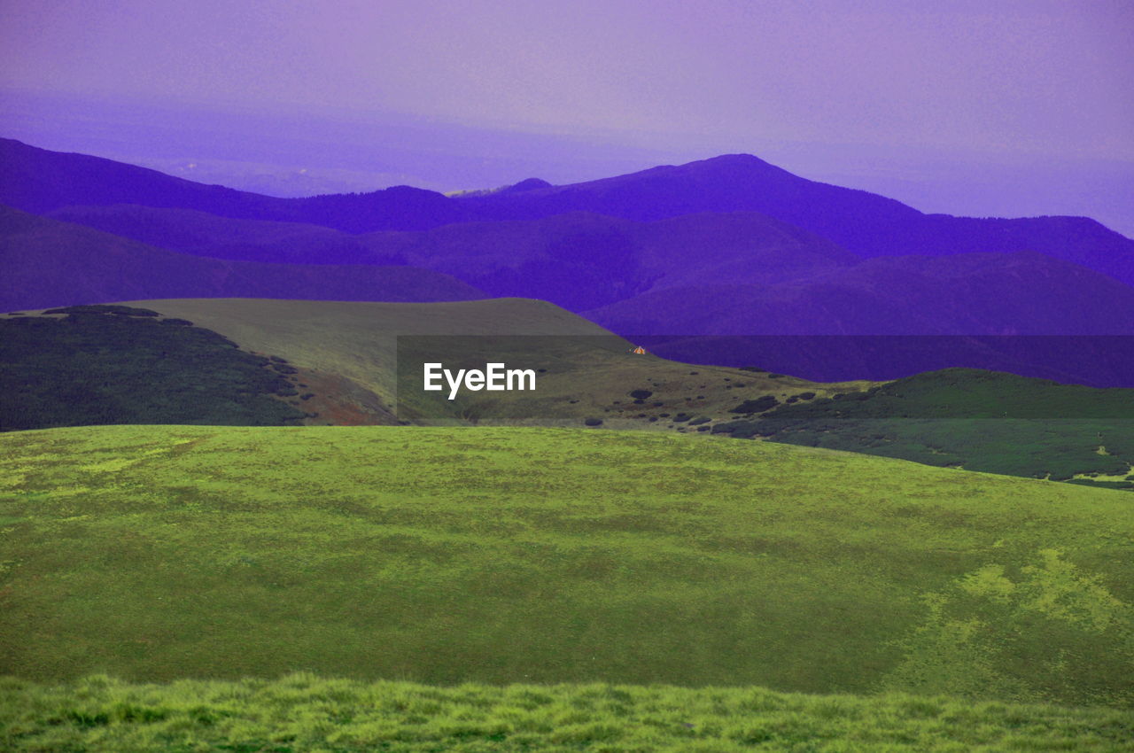 Grass covered mountain ranges against sky