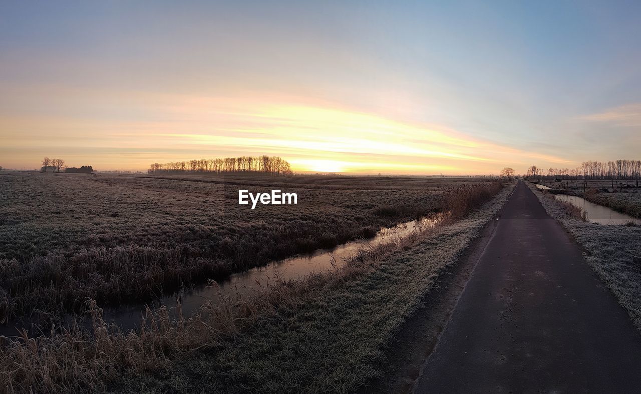 PANORAMIC VIEW OF ROAD ON FIELD DURING SUNSET