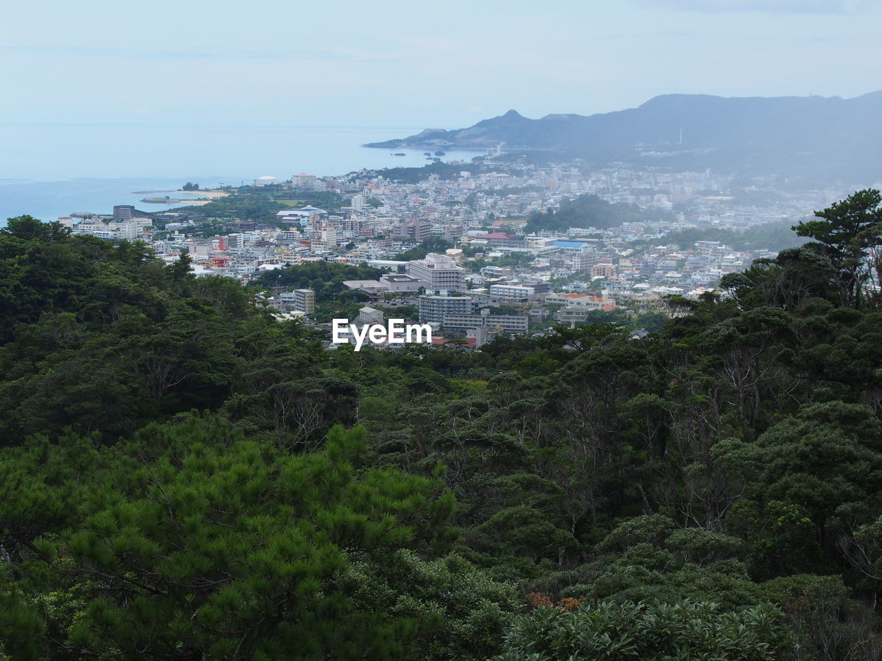 HIGH ANGLE VIEW OF CITYSCAPE AND SEA AGAINST SKY