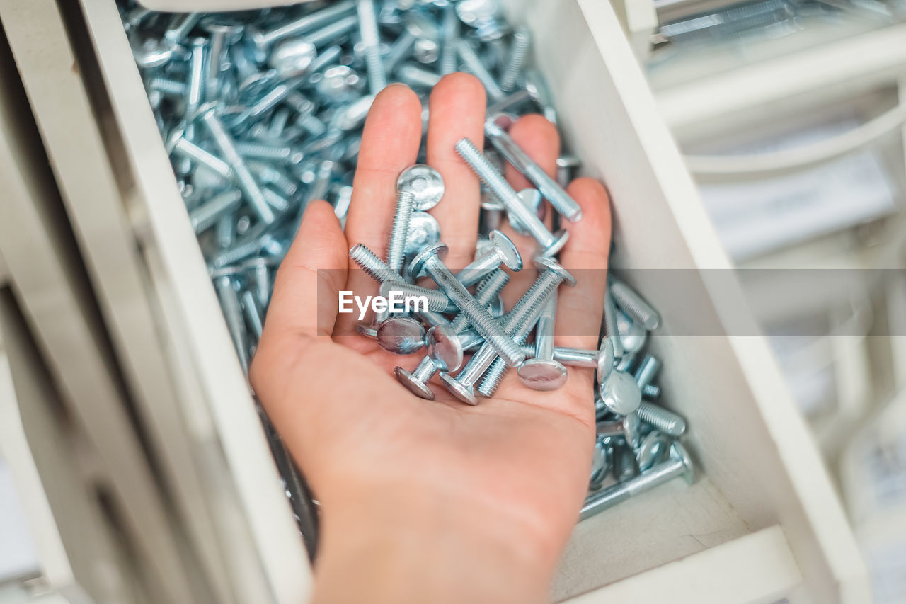 A lot of metal bolts on the palm of your hand. a handful of screws in the girl's hand