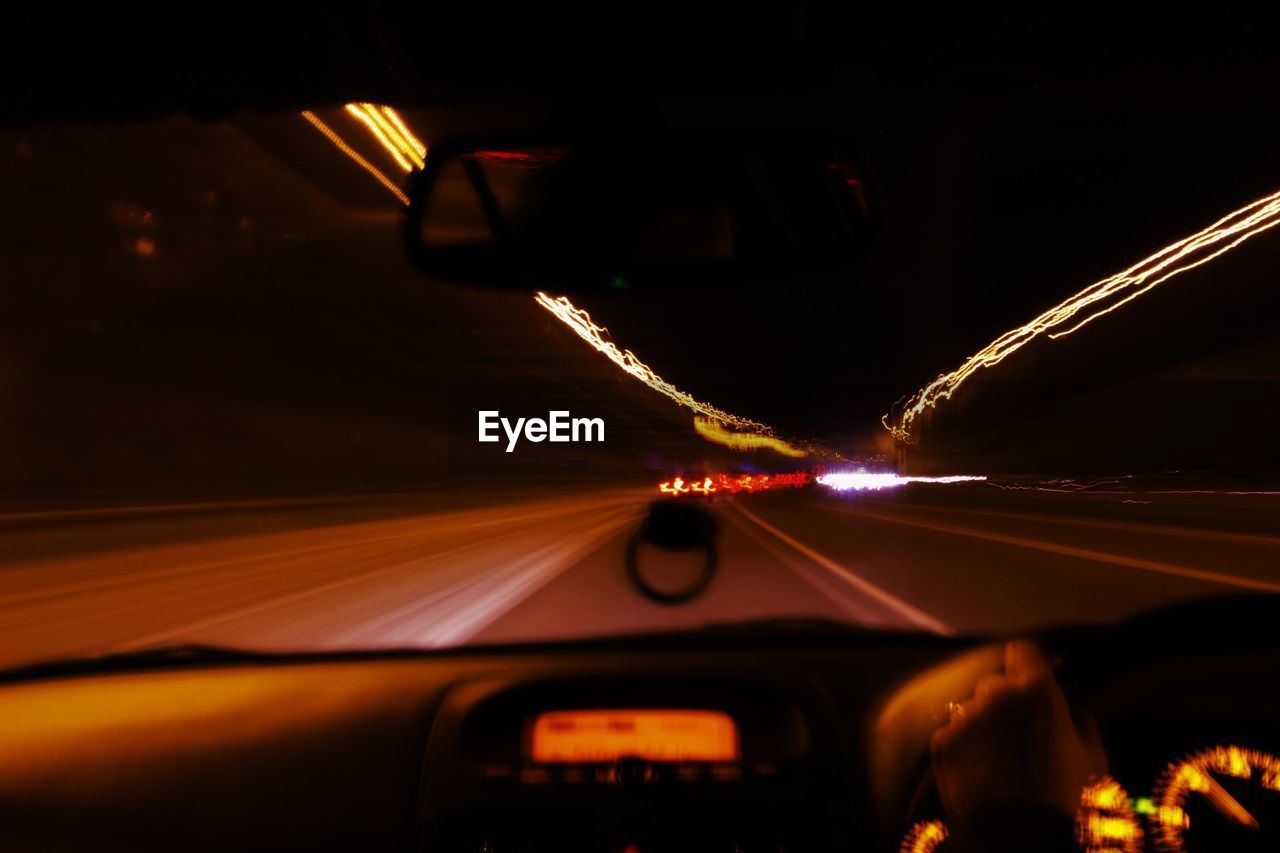 Light trails on road seen through car windshield at night