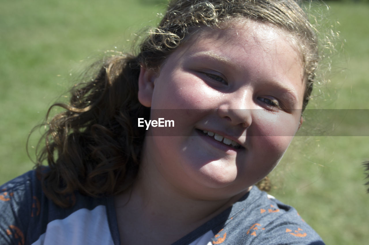 Close-up of smiling cute girl at field on sunny day