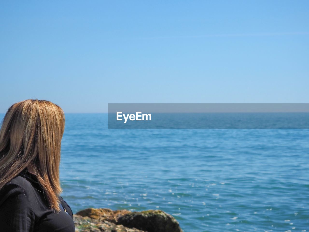 Side view of woman looking at sea against sky