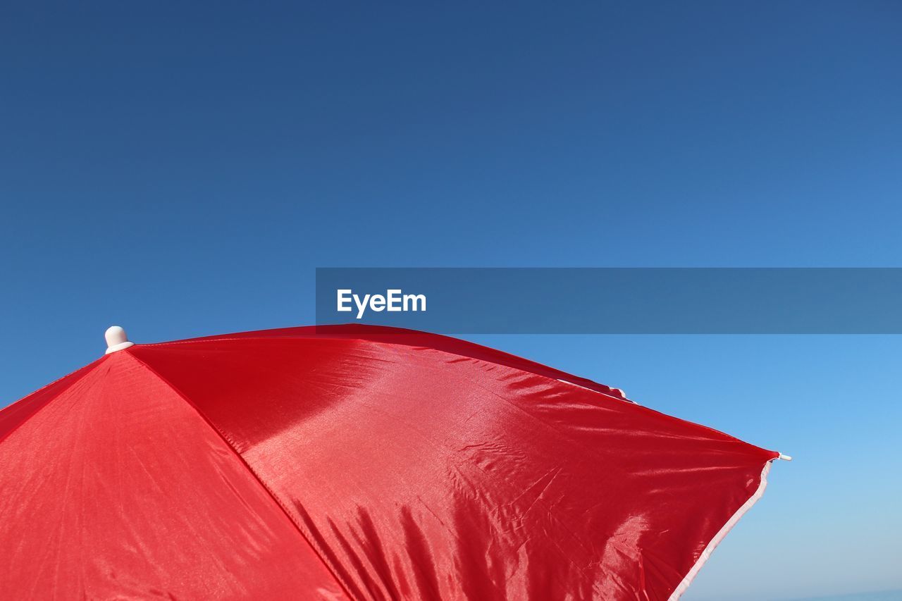 Cropped image of red umbrella against blue sky