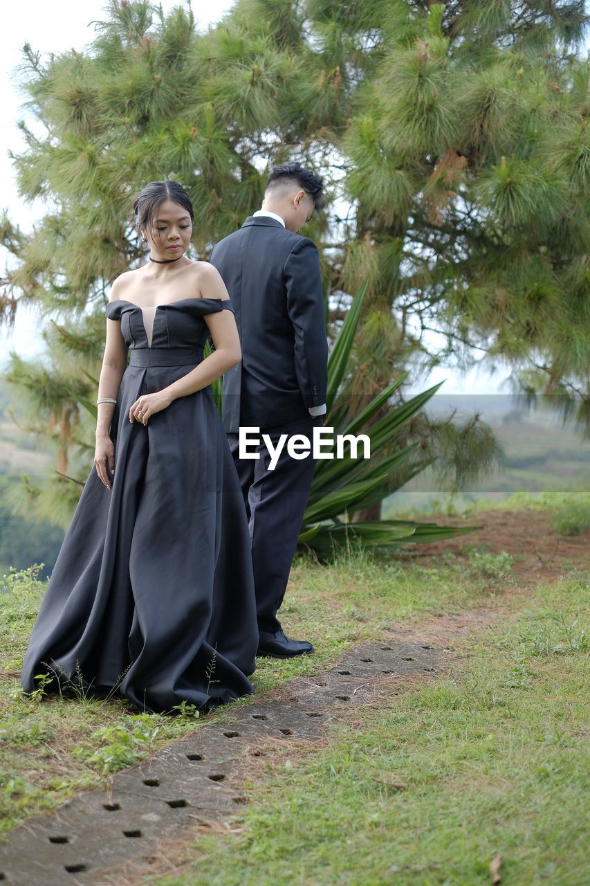 REAR VIEW OF COUPLE WALKING ON ROAD