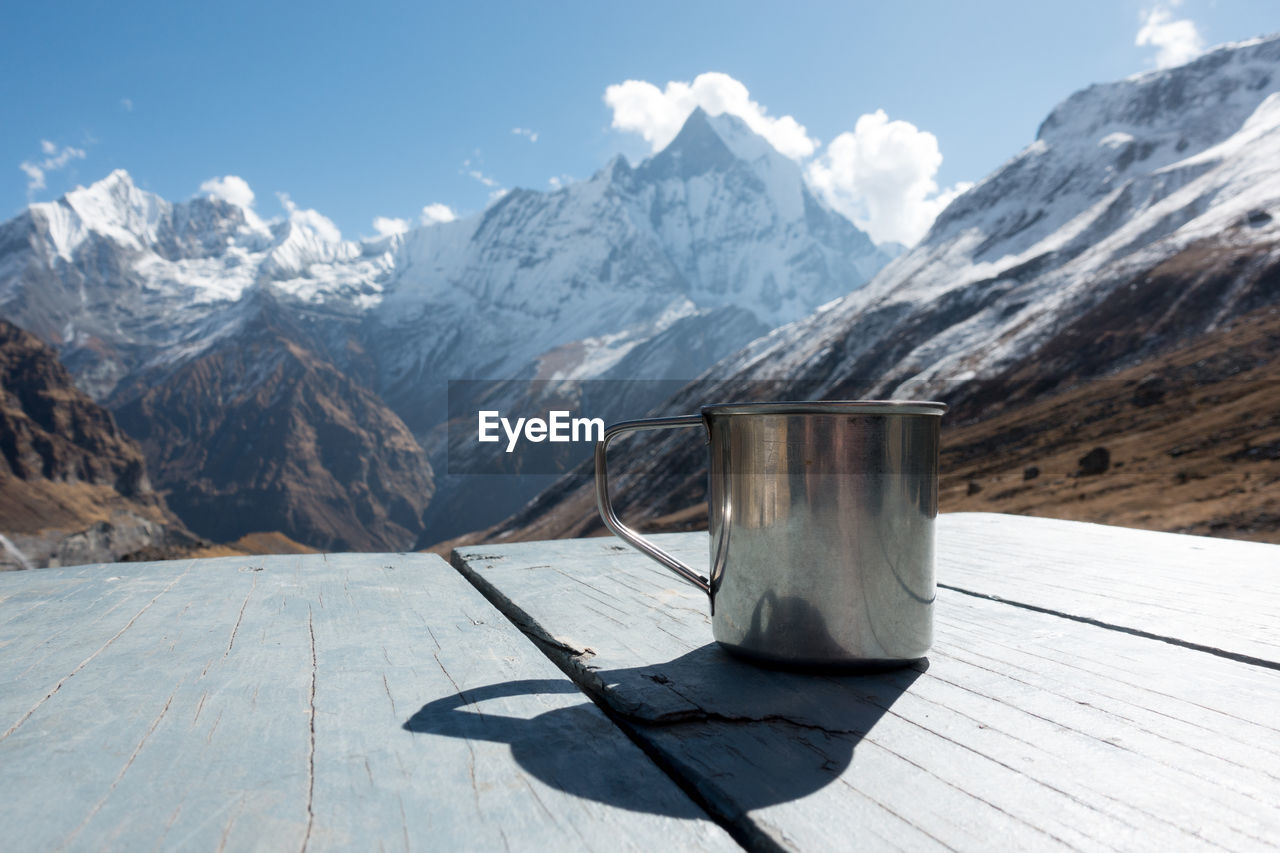 Close-up of mug on table against mountain range