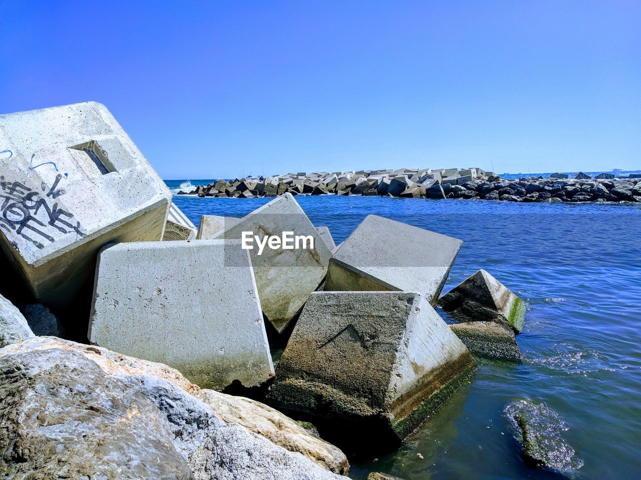 ROCKS BY SEA AGAINST CLEAR SKY