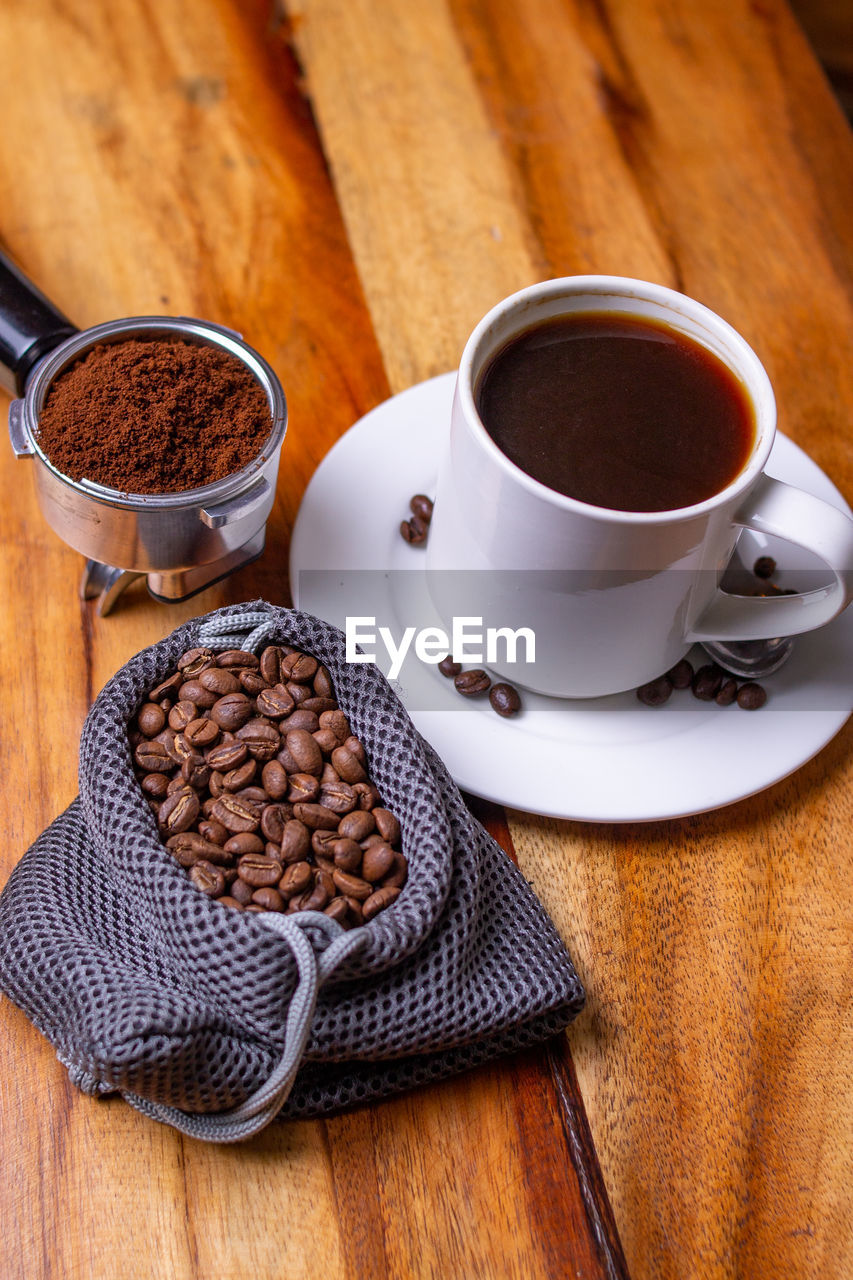 High angle view of coffee beans on table with a cup of coffee