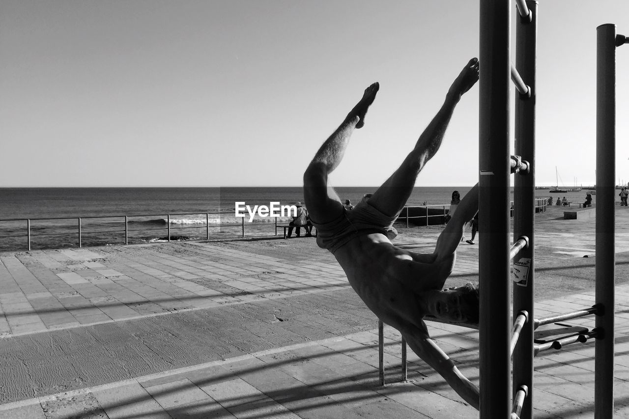 Man performing stunt at beach against sky