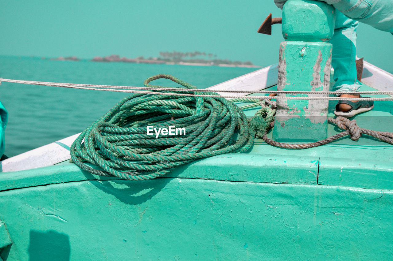 CLOSE-UP OF ROPE TIED UP ON METAL BOAT