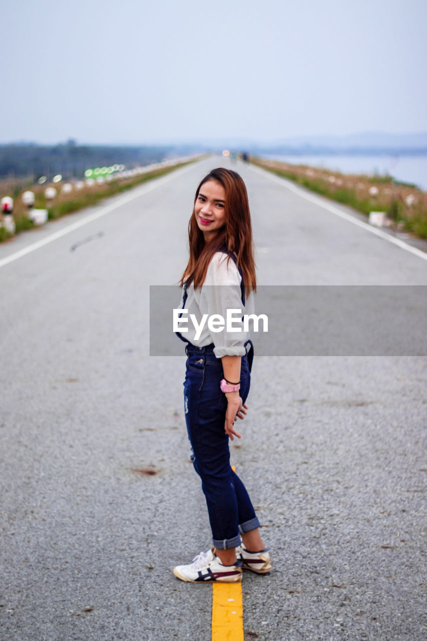 Portrait of smiling young woman standing on road