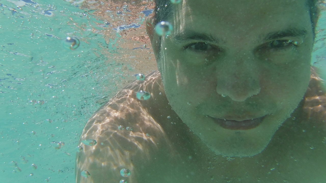 Portrait of young man swimming underwater in pool