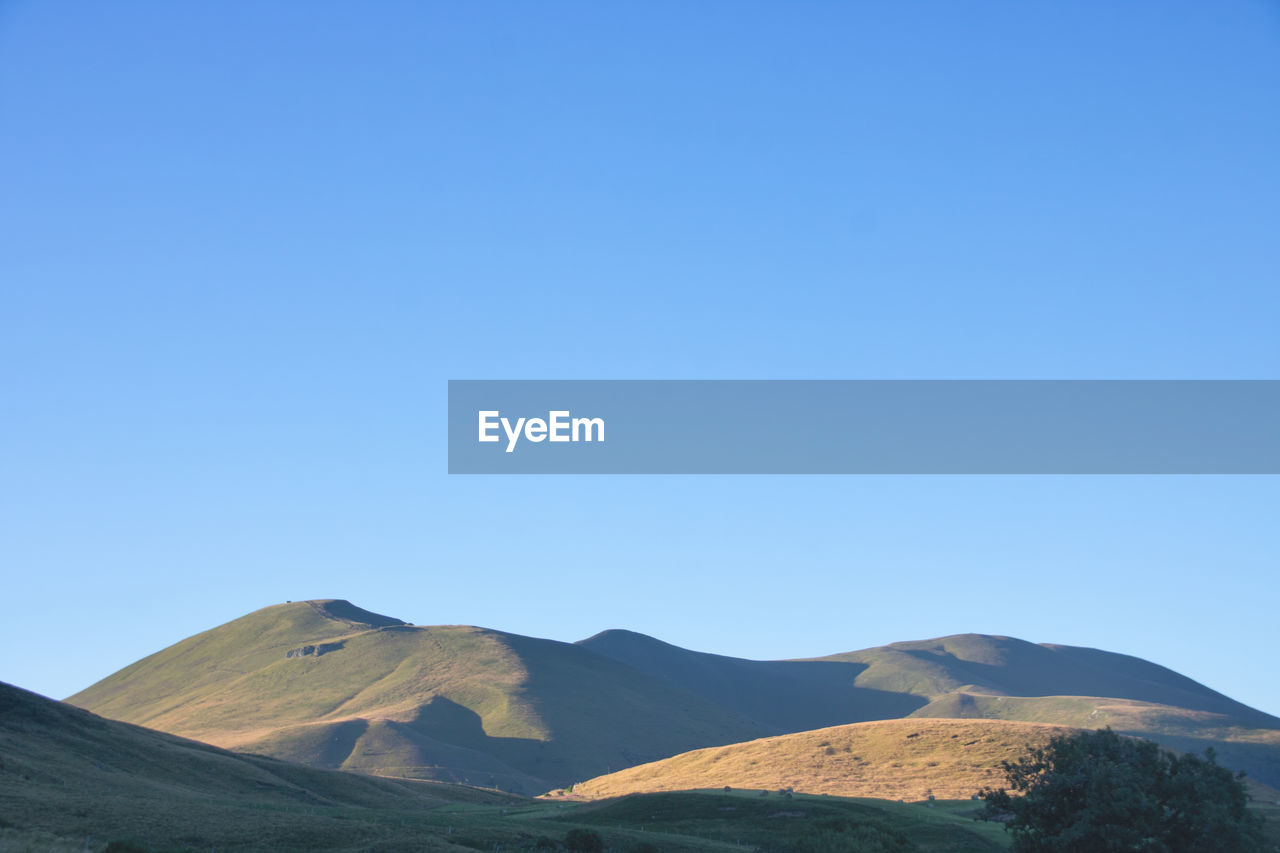 mountain, sky, landscape, scenics - nature, environment, blue, beauty in nature, nature, clear sky, land, no people, copy space, tranquility, non-urban scene, tranquil scene, mountain range, travel destinations, day, sunny, outdoors, horizon, travel, plateau, geology, ridge, plant, remote, physical geography, volcano, tourism