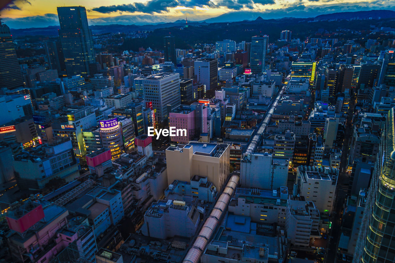 HIGH ANGLE VIEW OF ILLUMINATED MODERN BUILDINGS IN CITY AT NIGHT