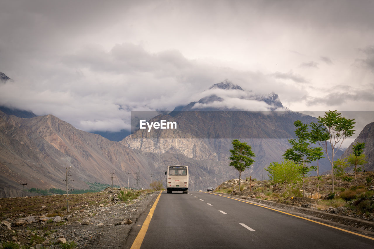 A bus passing the road over looking a beautiful snowy mountain