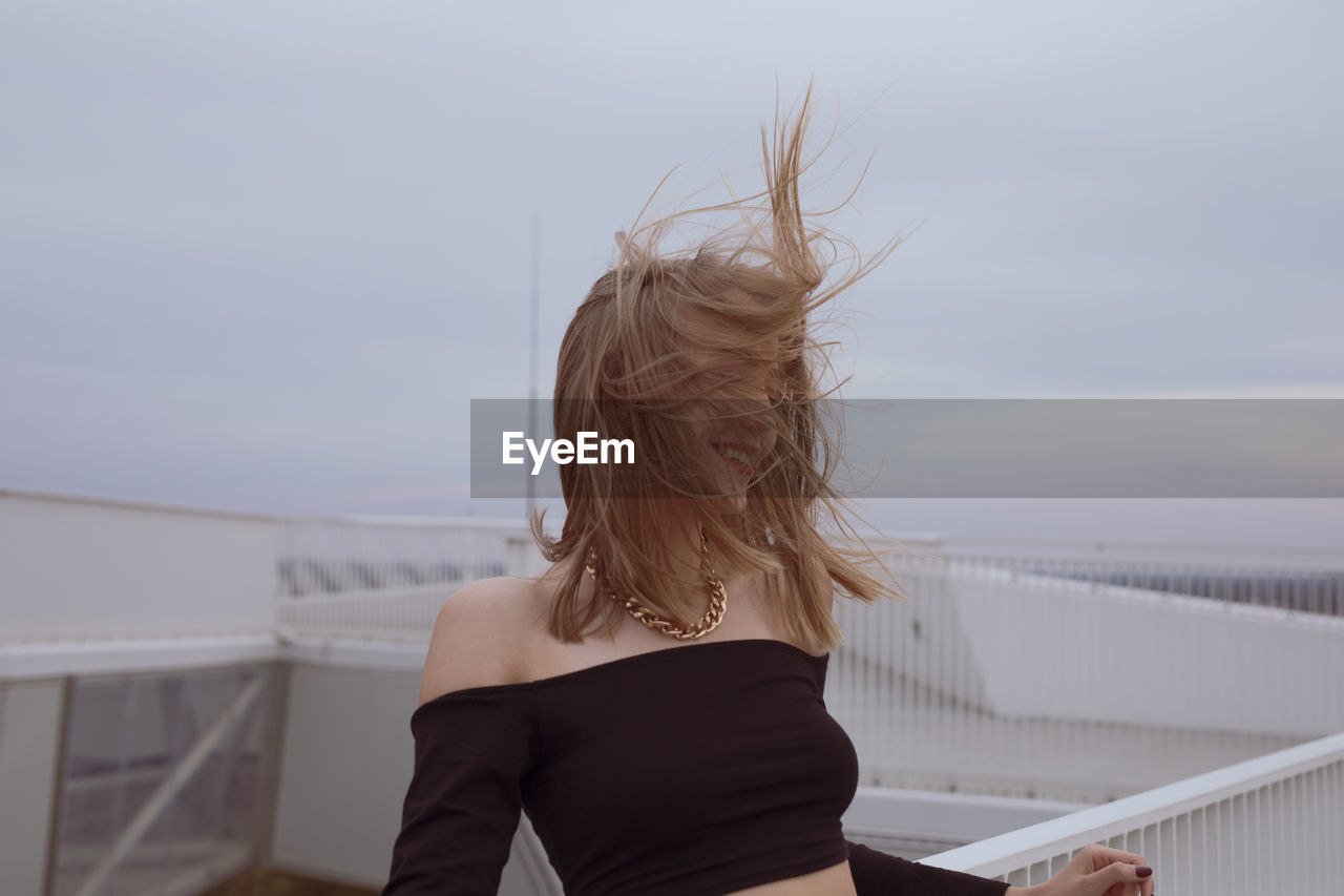 Woman standing by railing against sky