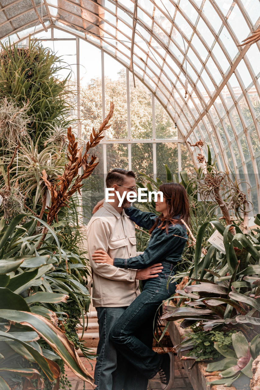 Portrait of young couple standing against plants
