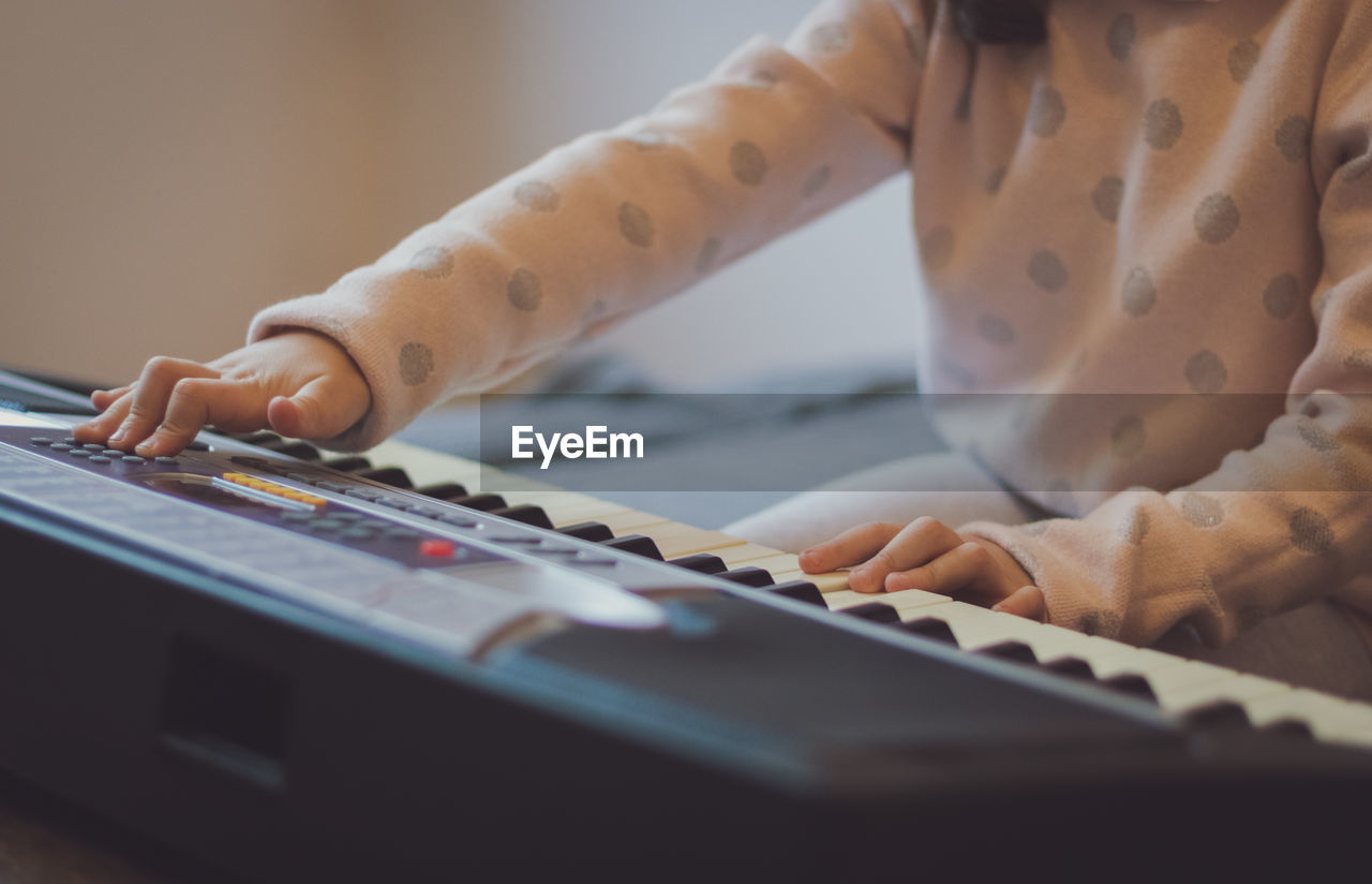 A little girl plays the electric piano.