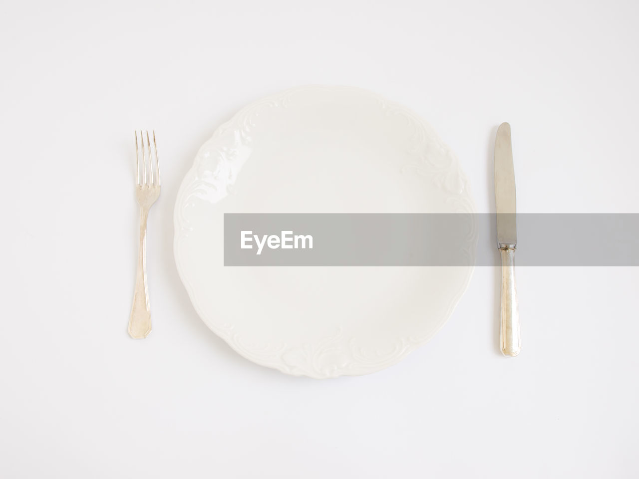 Directly above shot of plate and cutlery on white background