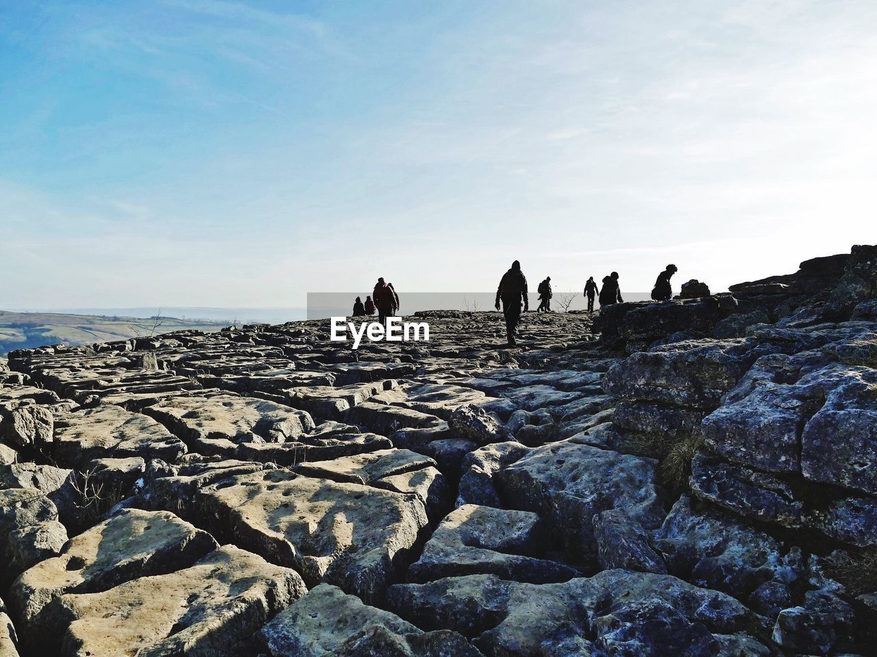 People walking on rocks against sky