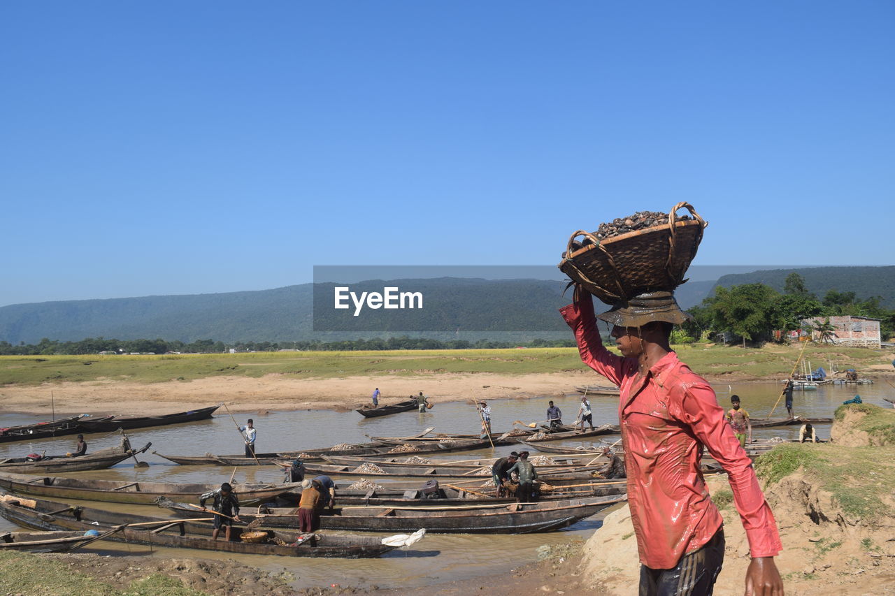 Man carrying basket on head against river